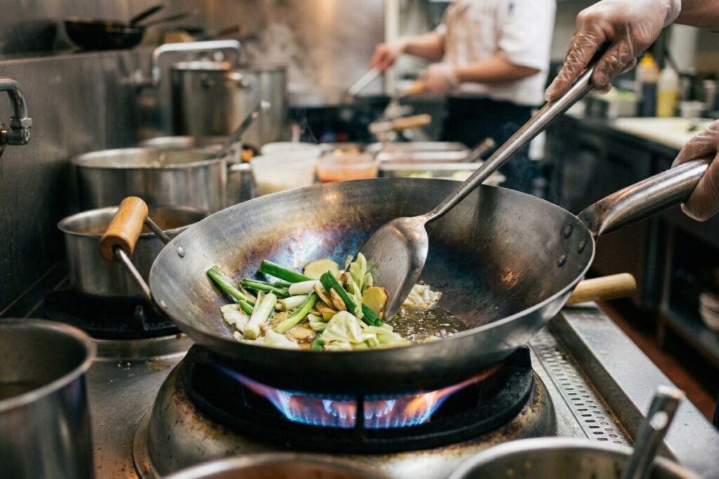 中華鍋の油慣らしで、金属臭を取り除き油膜を定着させるためにくず野菜を炒める様子