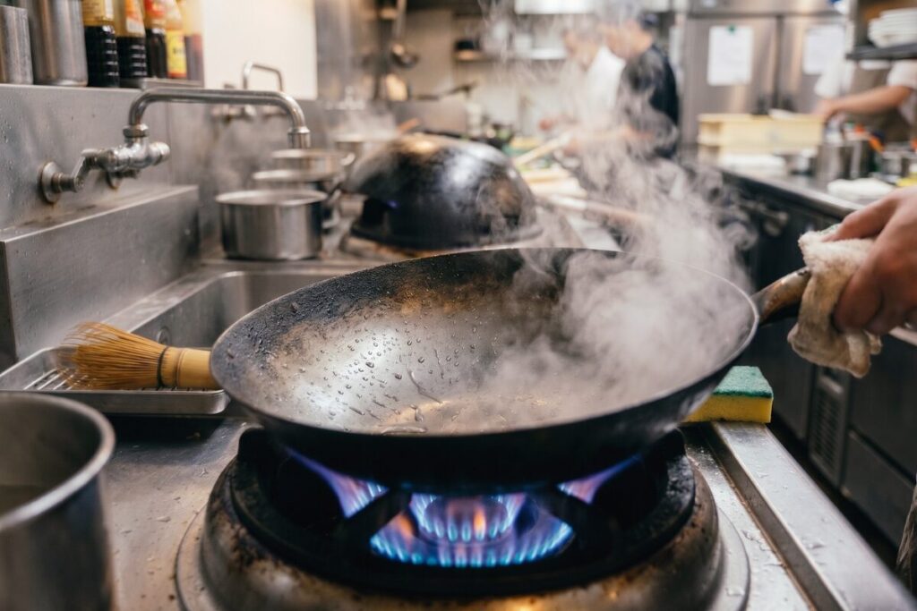 洗い終わった直後の中華鍋を強火にかけ、水分を完全に蒸発させて乾燥させる様子