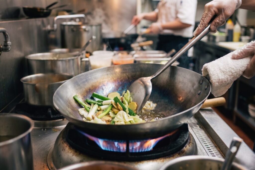 中華鍋の油慣らしで、金属臭を取り除き油膜を定着させるためにくず野菜を炒める様子