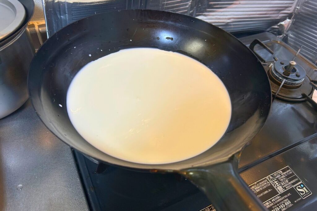 中華鍋で牛乳・生クリーム・水のベースを中火で温めている様子