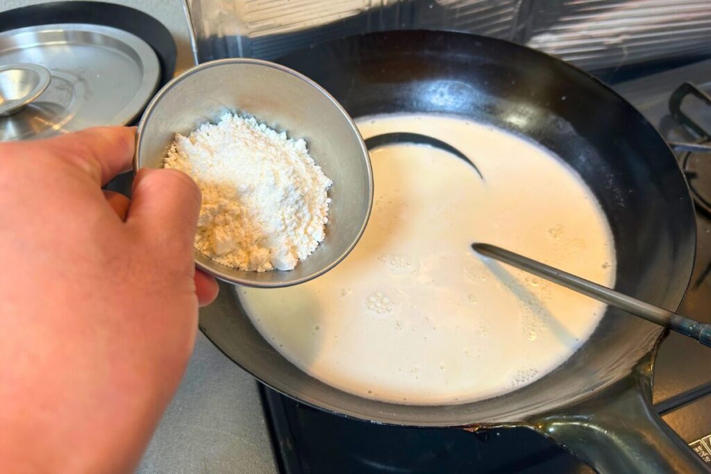 温めた液に杏仁霜を加えている様子