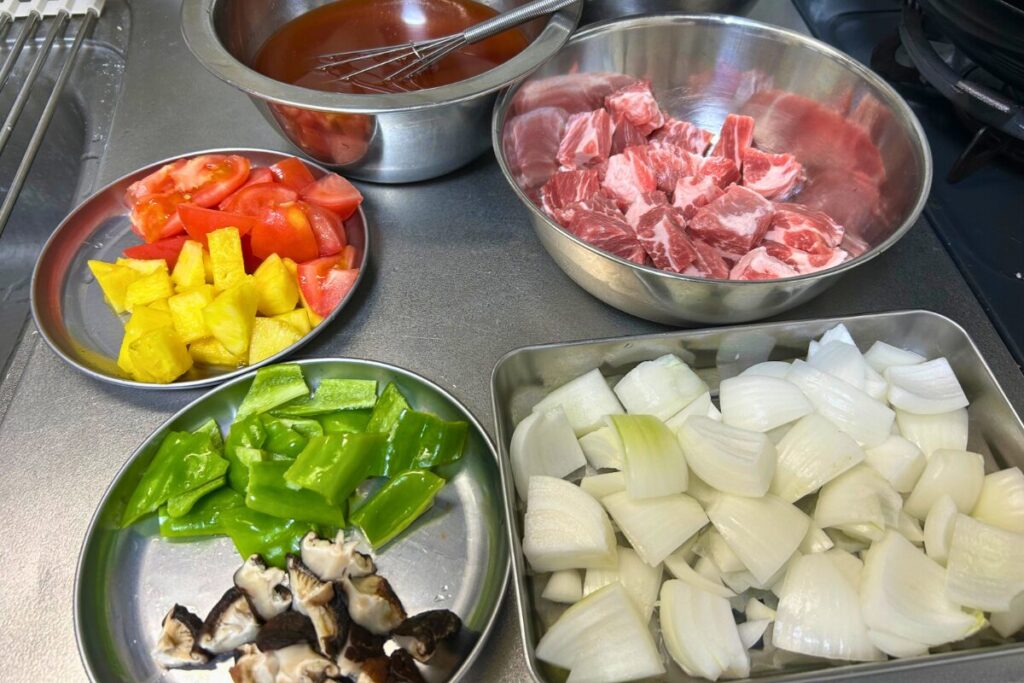 豚肩ロース・玉ねぎ・ピーマン・椎茸・パイナップル・トマトを一口大に切り揃えた様子