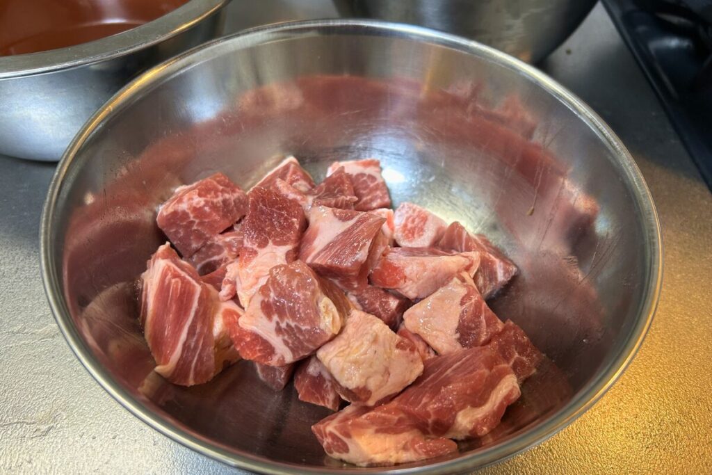 塩・胡椒・酒・醤油で下味①をつけた豚肩ロース。乱切りにした肉がボウルに入った状態