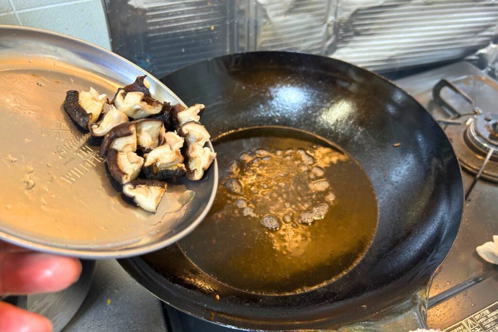 干し椎茸を油に入れる瞬間。火が通るまで時間がかかるため最初に油通しする