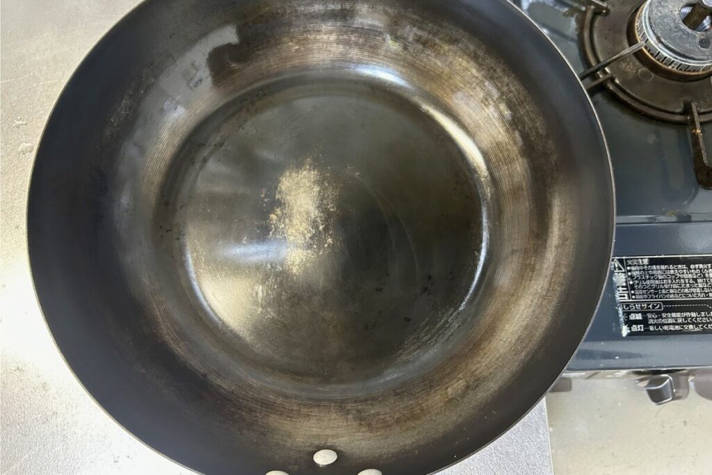 約1年使い込んだ鉄炒め鍋の内側を真上から。全体に育った油膜と中央の磨き跡