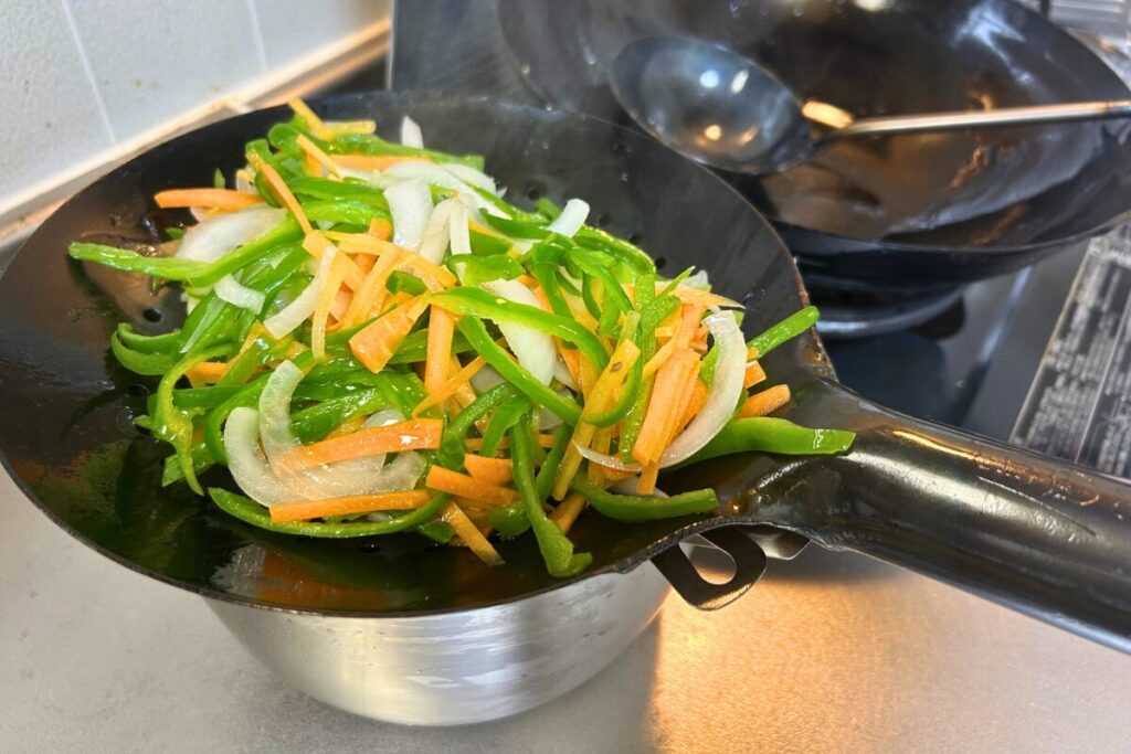 油通しした野菜をザーレンですくい上げたところ