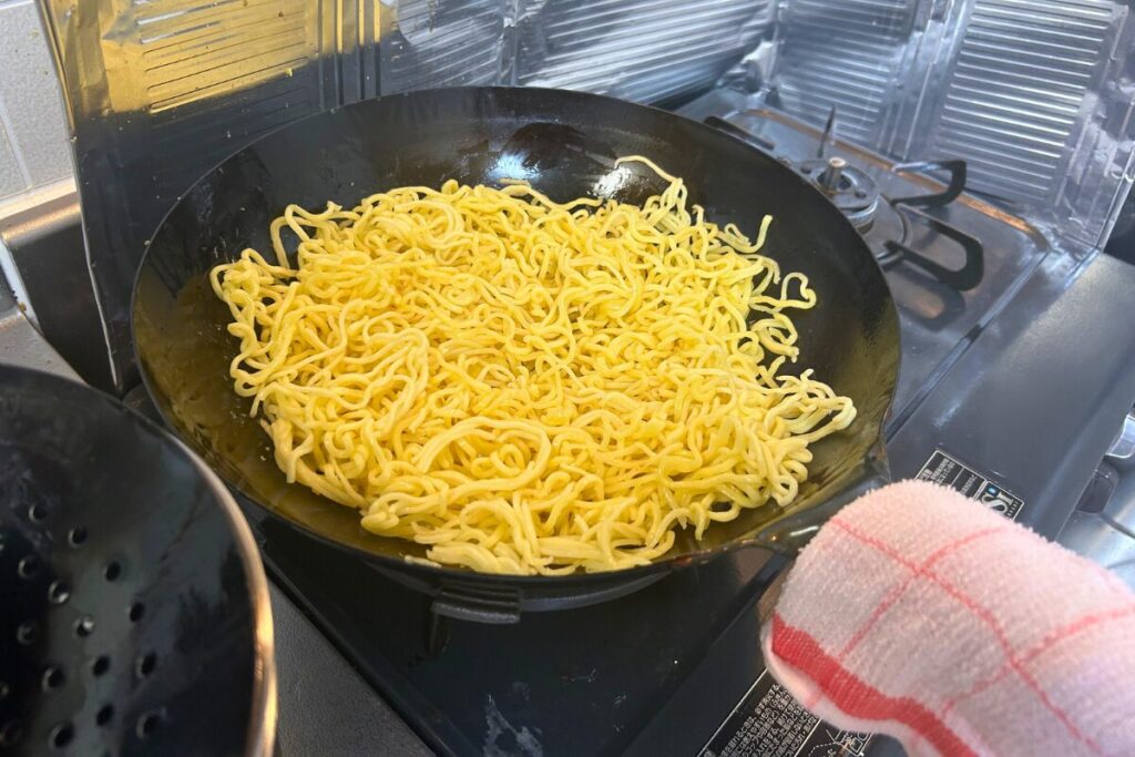 中華鍋で蒸し麺の両面を焼き付けている様子