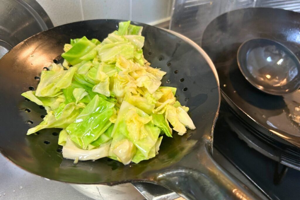 油通ししたキャベツをザーレンで油切りする様子