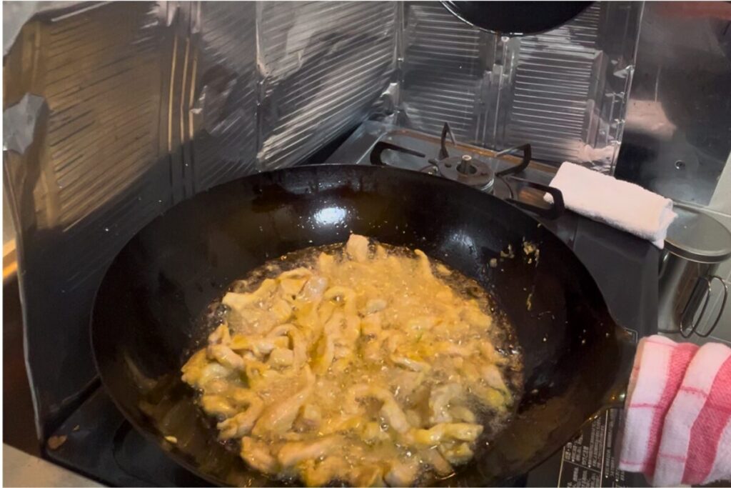 低温の油で豚肉細切りを油通ししている様子