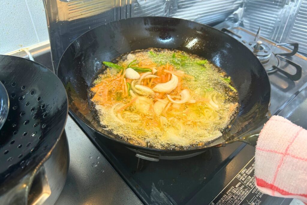高温の油で野菜を油通ししている様子。油通しは野菜と肉で狙いが真逆になる下ごしらえ