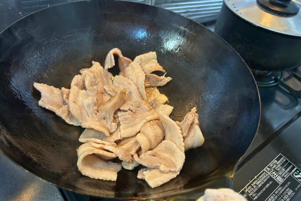 薄切り豚肉を弱め〜中火でじっくり炒めている様子