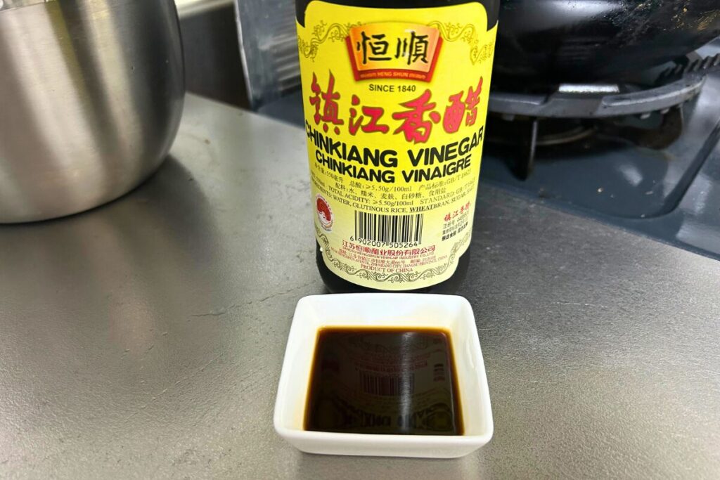 白い小皿に注いだ鎮江香醋。真っ黒でとろみのある見た目