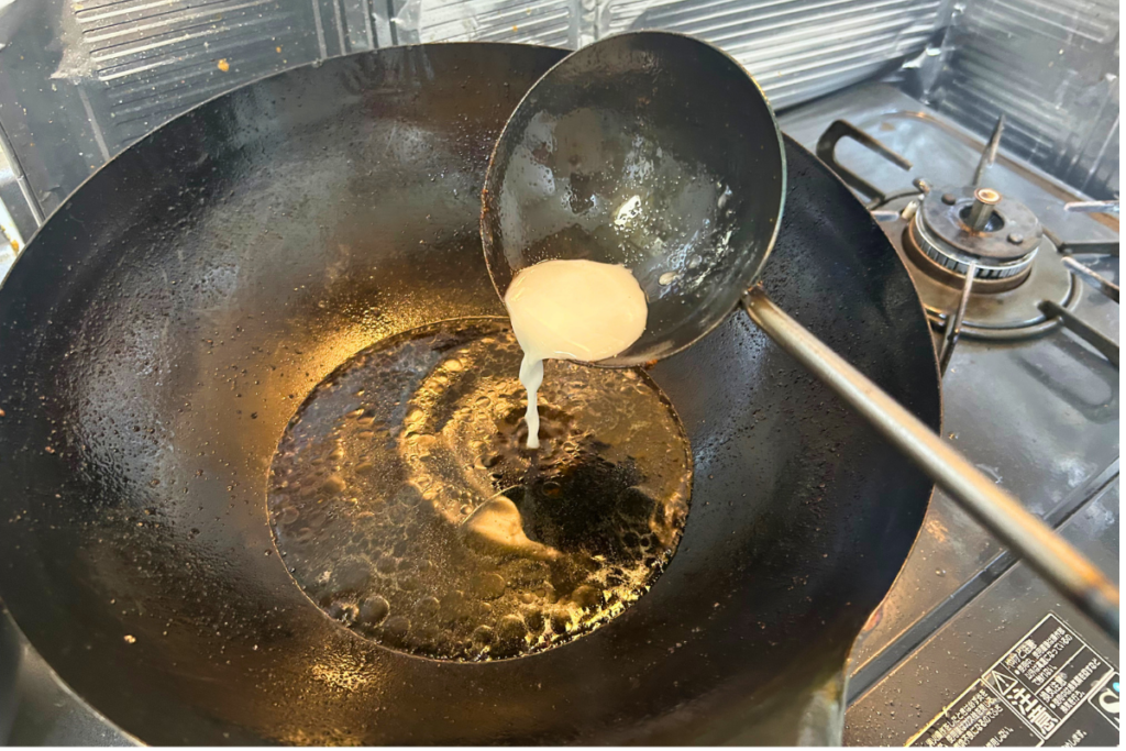 火を止めた黒酢だれに水溶き片栗粉を加えている瞬間