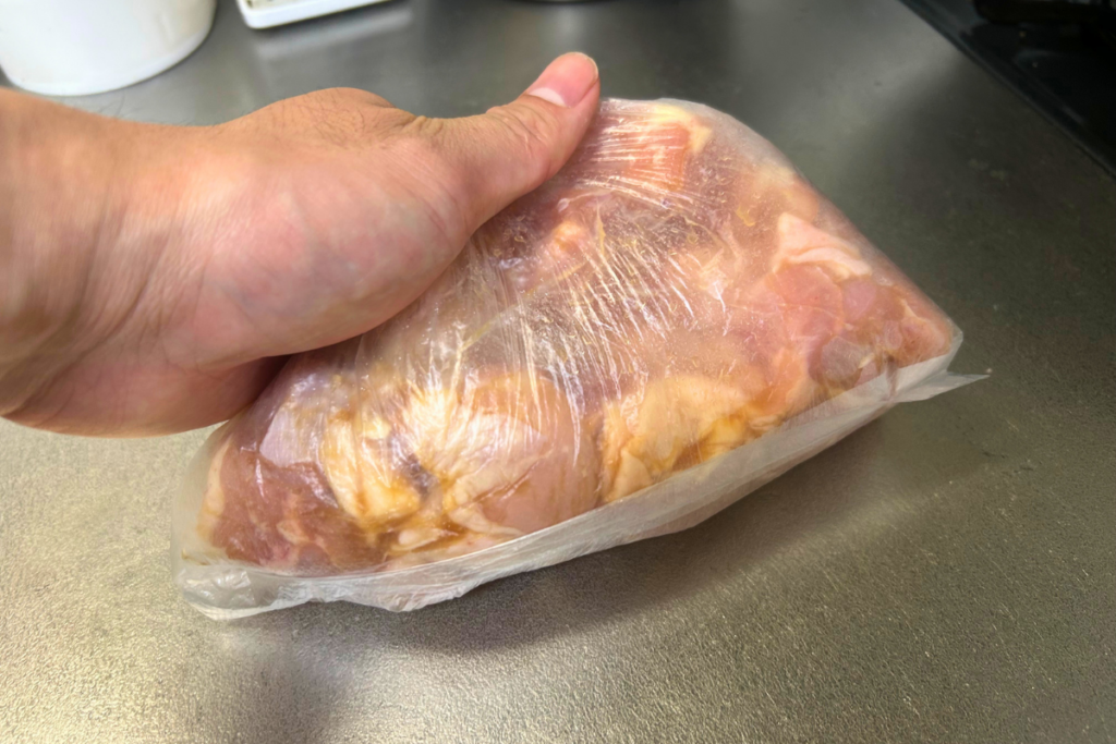 ポリ袋の上から鶏もも肉をもみ込んでいる手元