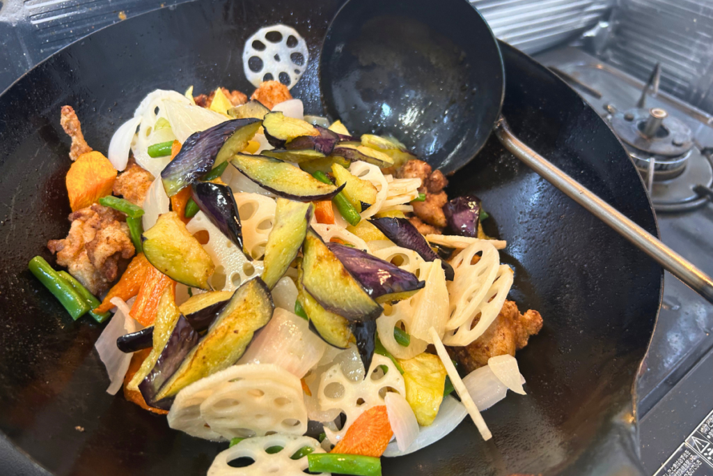 油通しした野菜と揚げた鶏を、とろみのついた黒酢だれの鍋に戻す