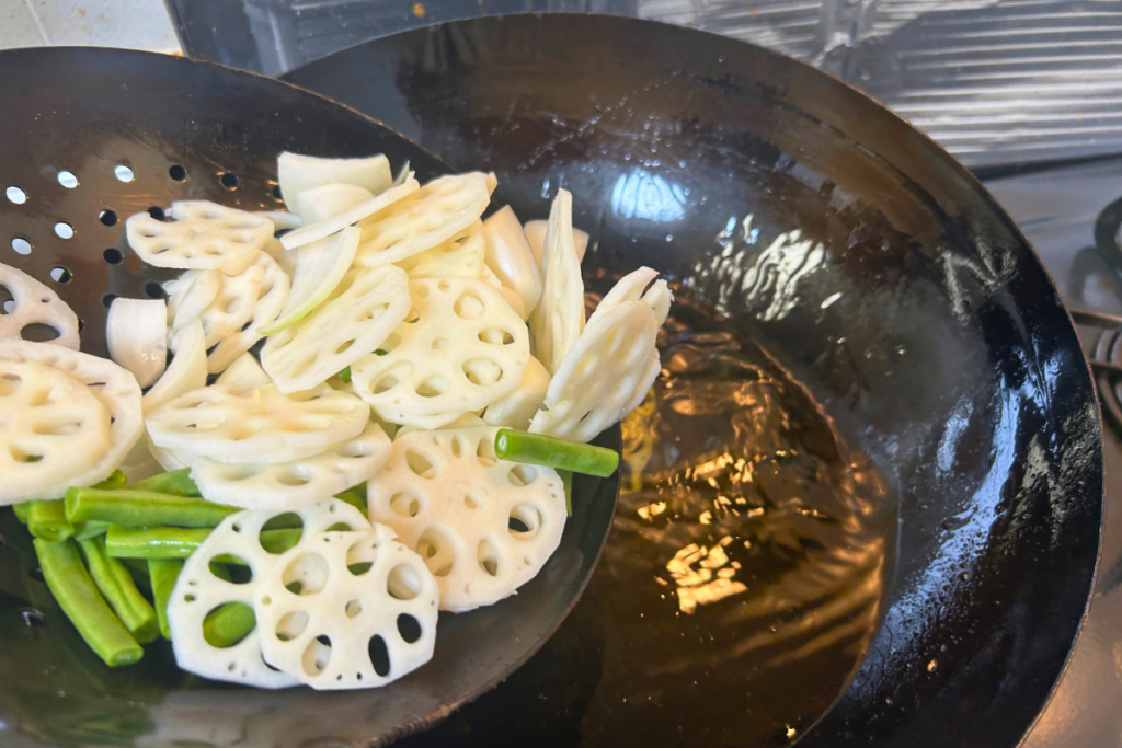 煙が少し増えた油に、いんげん・玉ねぎ・れんこんを入れる瞬間