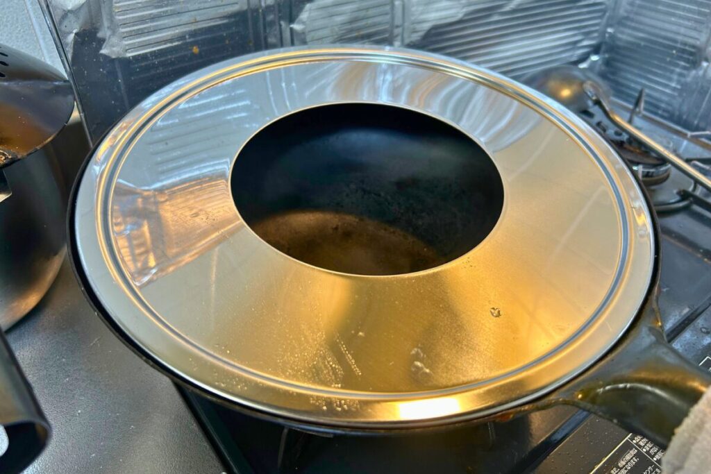 中華鍋にステンレス蒸し板だけを乗せ、中心の穴から鍋の内側が見えている状態