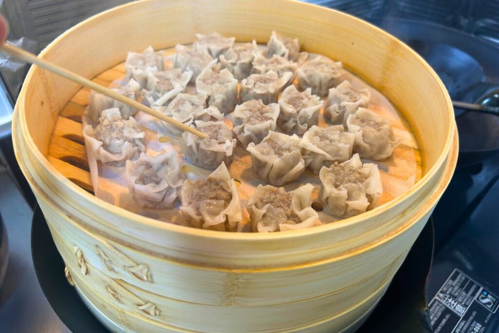 蒸している途中のシュウマイに竹串を刺して、火の通りを確認している様子