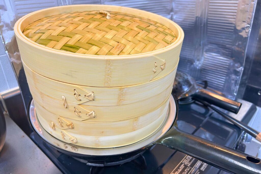 蒸し板を挟むと、竹せいろの底が中華鍋のフチとほぼ同じ高さになる様子