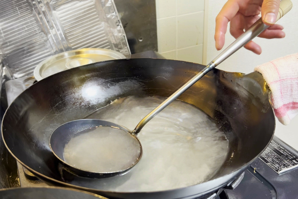 お玉でスープをすくい、味を確かめているところ
