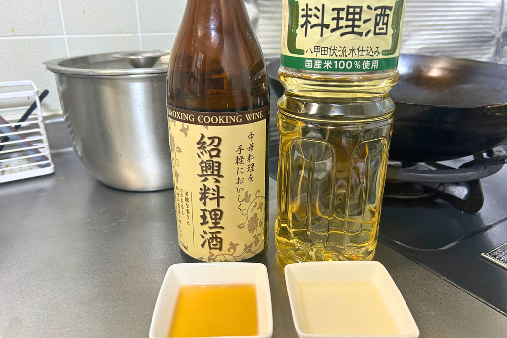 紹興料理酒とワダカン料理酒の瓶を並べ、それぞれを小皿に注いで比べている様子