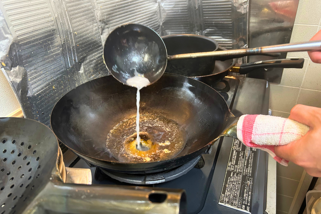 火を止めた合わせ調味料に、水溶き片栗粉を少しずつ加えている場面