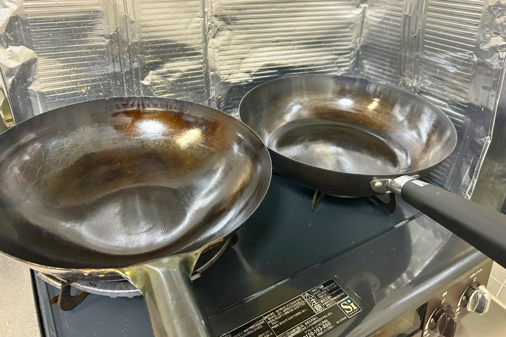 山田工業所の中華鍋(左)とニトリの鉄炒め鍋(右)。入門用から一生モノへのステップアップを示す2本