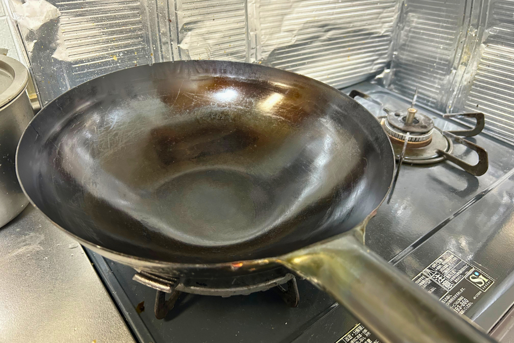 打出し式の鉄製中華鍋(山田工業所)。使い込まれた鍋肌の質感が伝わる一枚