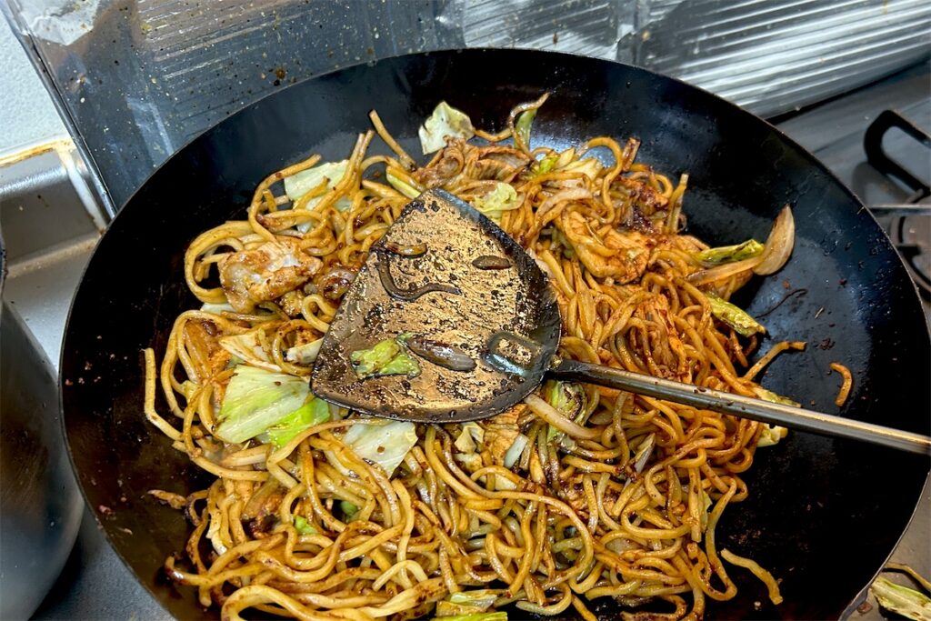 焼きそばを炒める、使い込んで黒くなった鉄製の中華ヘラ