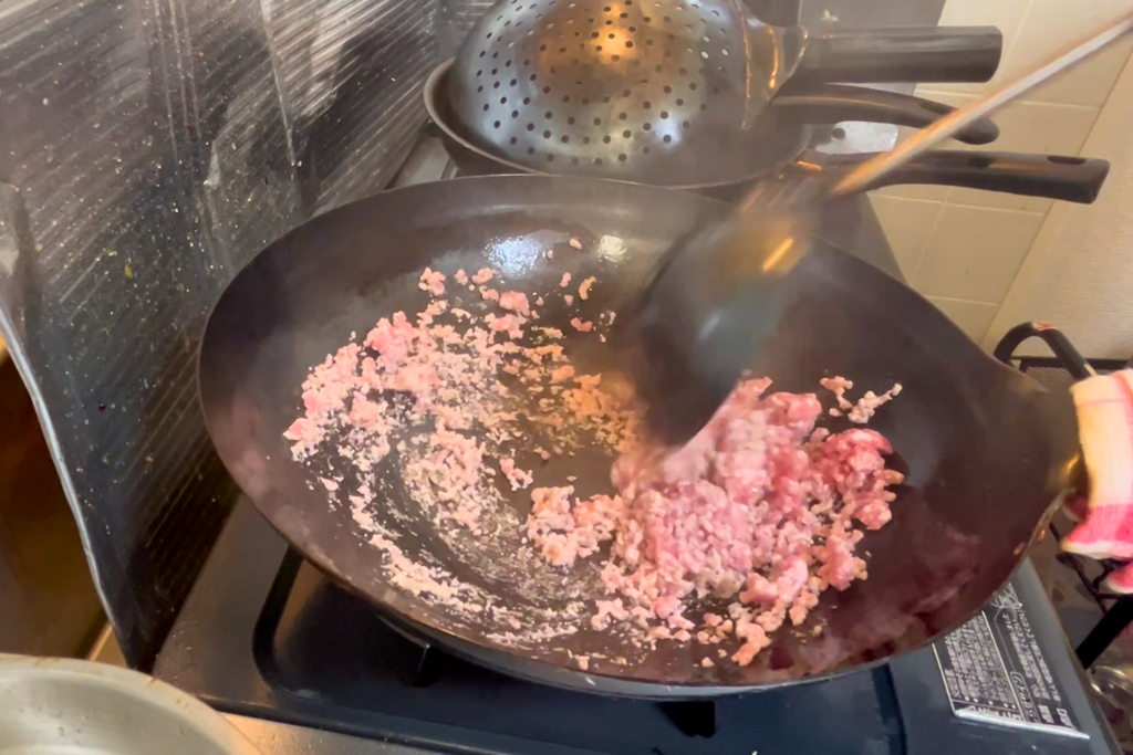 中華鍋でほぐしながら炒め、白っぽい部分と赤い部分が混ざった豚ひき肉