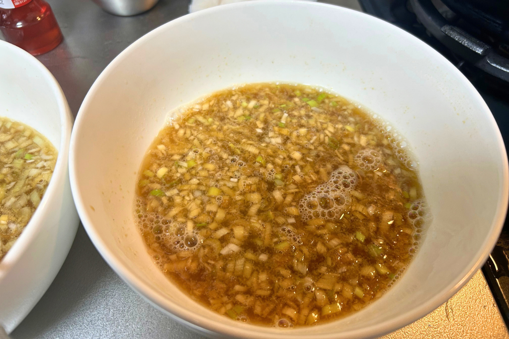 芝麻醤の塊がなくなるまで溶きのばした担々麺のスープ。葱花が全体に散っている