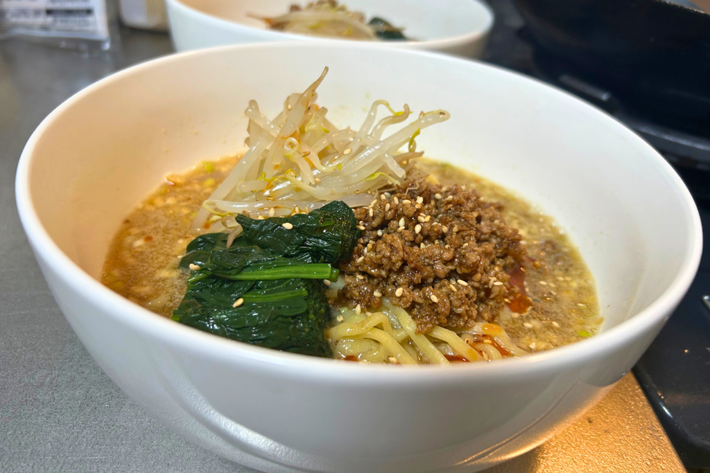 低い角度から見た担々麺。ごまのスープに肉味噌ともやし、ほうれん草をのせ、白ごまを振っている