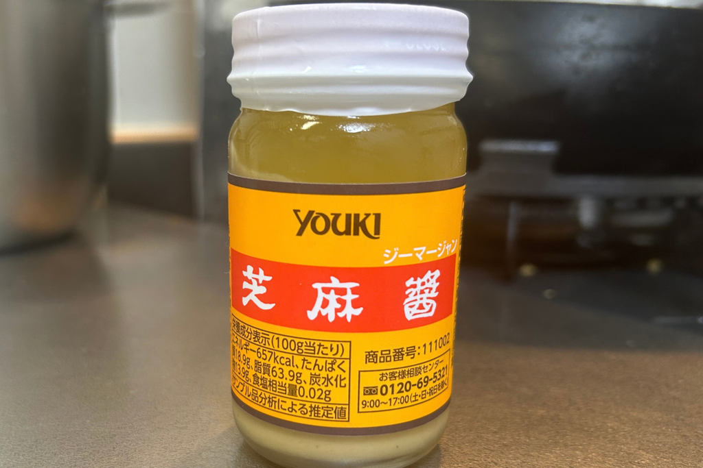 ユウキ食品の芝麻醤の瓶。上に透明な油が浮き、底にごまのペーストが沈んでいる。ラベルに栄養成分表示がある