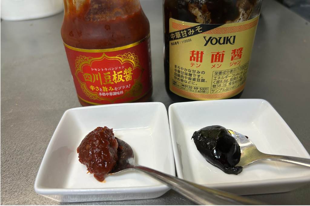 僕の家の豆板醤(左)と甜麺醤(右)を小皿に取って並べた様子。色も質感も違い、入れ替えると料理の味の方向が変わる