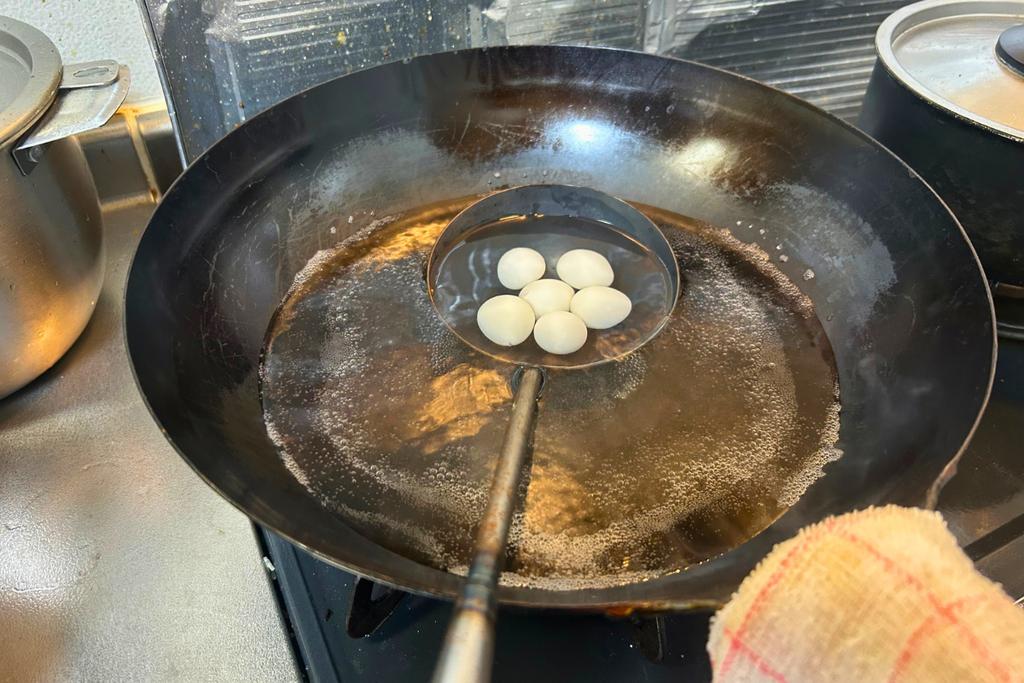 塩を入れた湯に、うずらの水煮をお玉ごと通す様子。