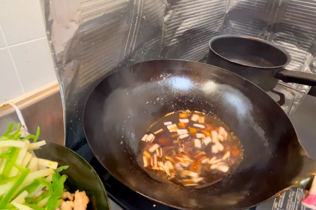 空いた中華鍋で、葱と生姜の入った合わせ調味料を温めているところ