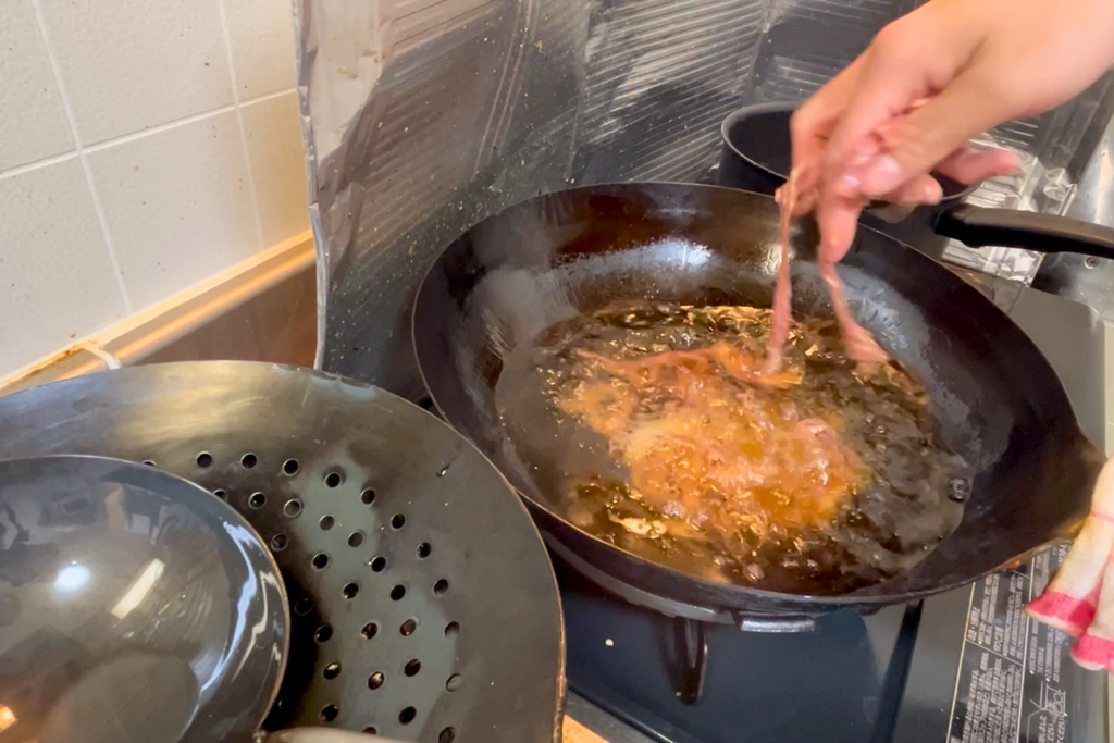 チャンをした豚肉を、中華鍋の油に入れる瞬間